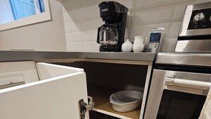 A compact kitchen with a refrigerator, oven, and coffee maker.
