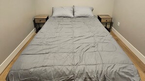A bedroom with a large bed, two bedside tables, and a wall-mounted light fixture.