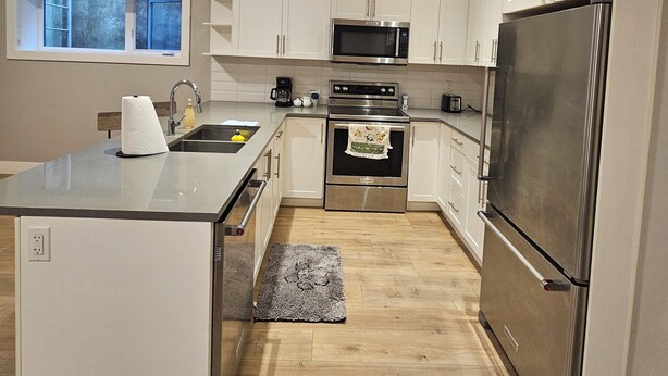 A modern kitchen with white cabinets, stainless steel appliances, and a large island.