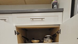 A kitchen with white cabinets, a stainless steel sink, and a wooden floor.