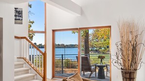 A modern interior with a staircase leading to a balcony overlooking a lake.