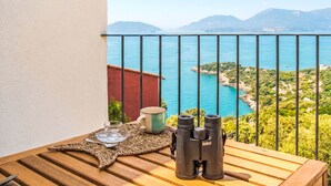 En balkon med havudsigt, kikkert, krus og måtte.