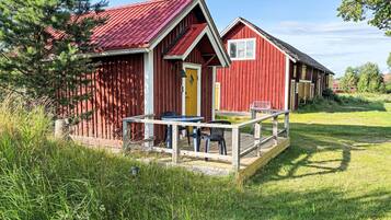 A red wooden building with a yellow door and a small outdoor seating area with a table and chairs.