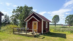 A small wooden cabin with a porch, a door, and a window.