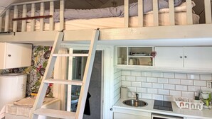 A bunk bed with a kitchen area below, including a sink and cabinets.