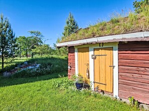 Ein rustikales Holzhaus mit grüner Dachdeckung, umgeben von üppiger Vegetation und Bäumen.