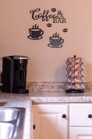 Eine Küche mit Kaffeemaschine, Kaffeetassen-Wanddeko und einer Kapselhalterung.