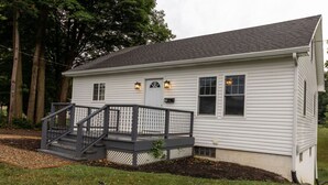 A single-story house with a front porch, a small staircase, and a mailbox.