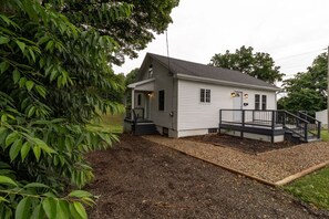 Ein eingeschossiges Haus mit Veranda, kleiner Terrasse und Kiesweg.
