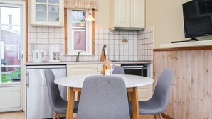 A compact kitchen with a dining area, featuring a refrigerator, a stove, a sink, and a television.