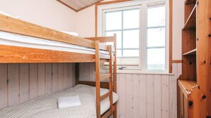 A bunk bed room with a window and wooden walls.