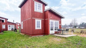 A red two-story building with a patio area and a barbecue grill.