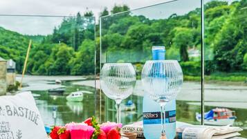 A table with a bottle of water, two glasses, a plate of strawberries, and a newspaper.