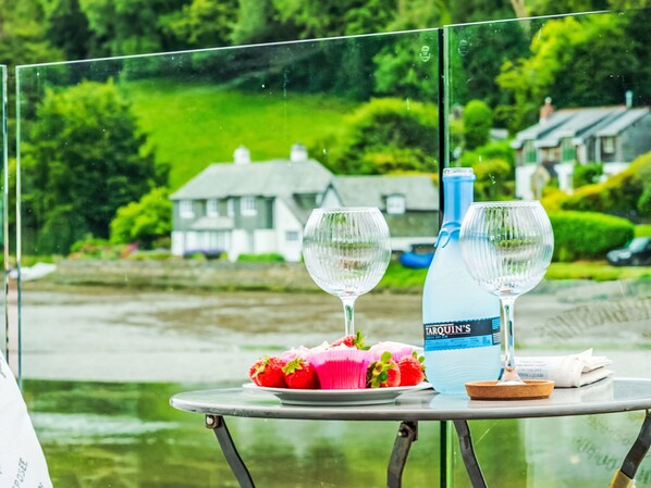 A table with two wine glasses, a bottle of water, and a plate of strawberries.