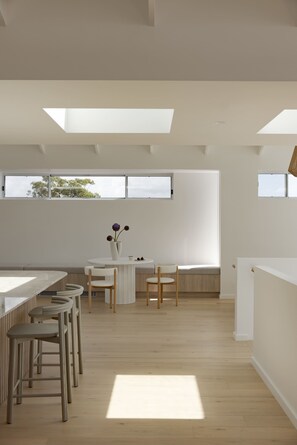 A modern interior with a dining area, a white table, and a vase with flowers. - The View (Gerringong)