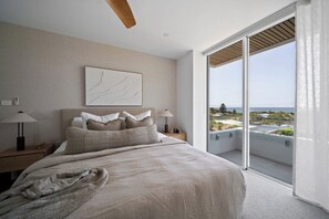 A bedroom with a large bed, a view of the city, and a balcony with a view.