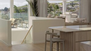 A modern kitchen with a central island, a dining area with a bar stool, and a view of the city through large windows.