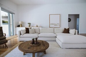 Una sala de estar moderna con un sofá modular, una mesa de centro de madera y un ventanal grande.