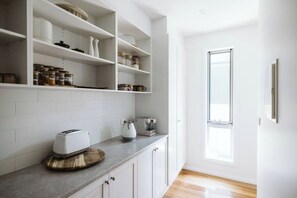 Una cocina moderna con armarios blancos, encimera de granito y ventana que deja entrar luz natural.