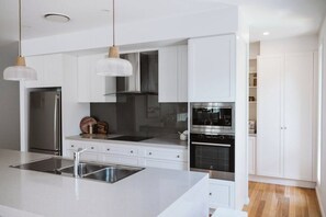 Una cocina moderna con armarios blancos, electrodomésticos de acero inoxidable e iluminación colgante.