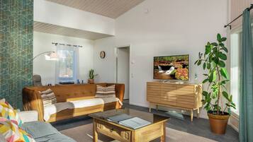 Een woonkamer met een bank, salontafel en een televisie op een houten kast.