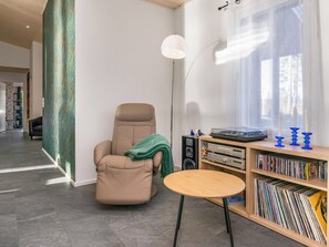 A modern living room with a recliner, a small round table, a bookshelf with vinyl records, and a floor lamp. - Järven idylli by Interhome (Ruokolahti)