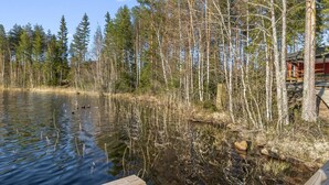 A wooden dock extending into a calm lake surrounded by dense trees.