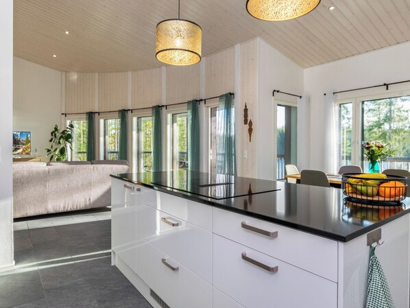 A modern kitchen with a large island, white cabinetry, and a dining area with a table and chairs.