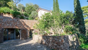 Un edificio de piedra con un muro de piedra y un árbol en primer plano.
