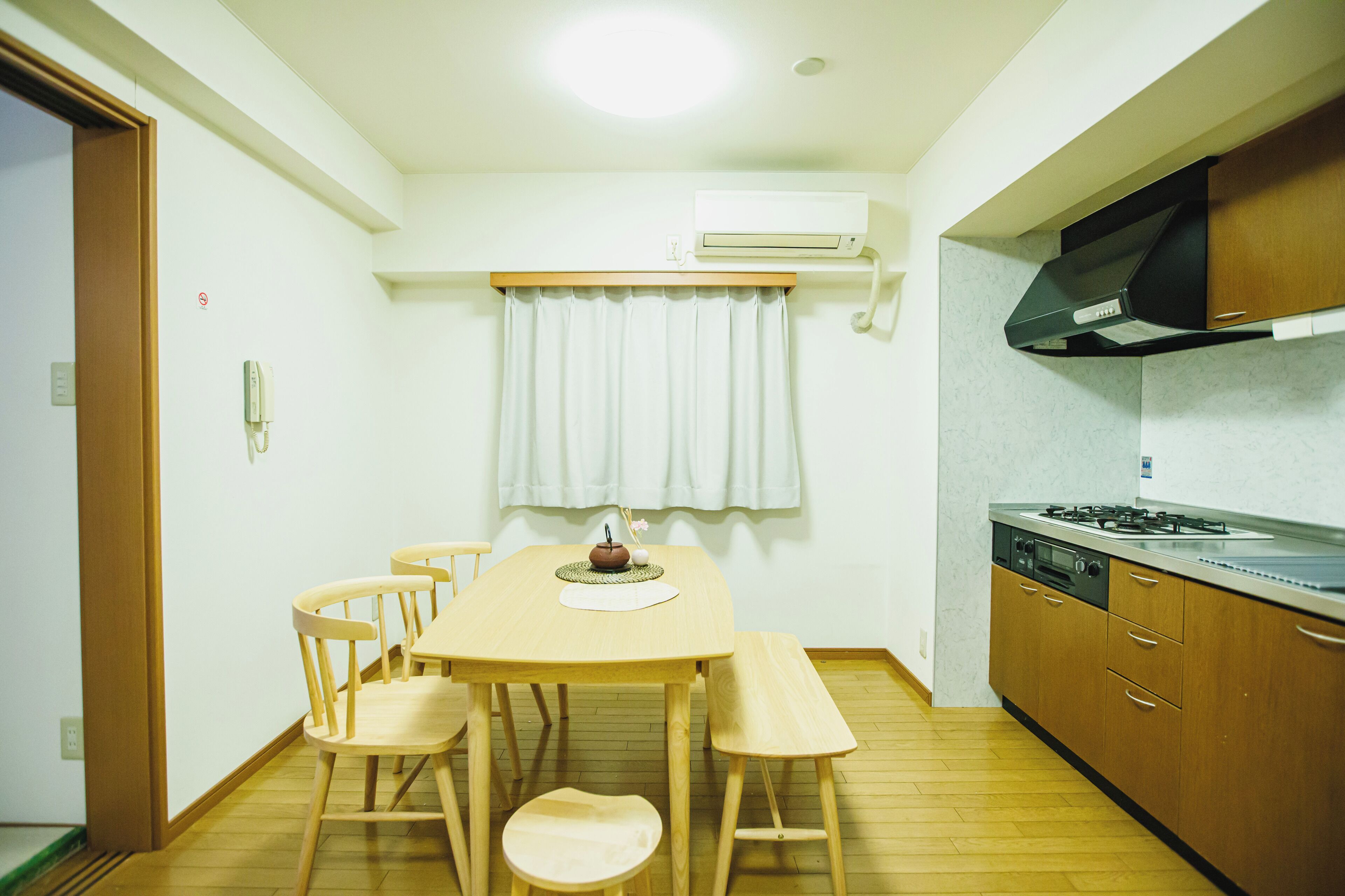 Una cocina compacta con una mesa, sillas y estufa.