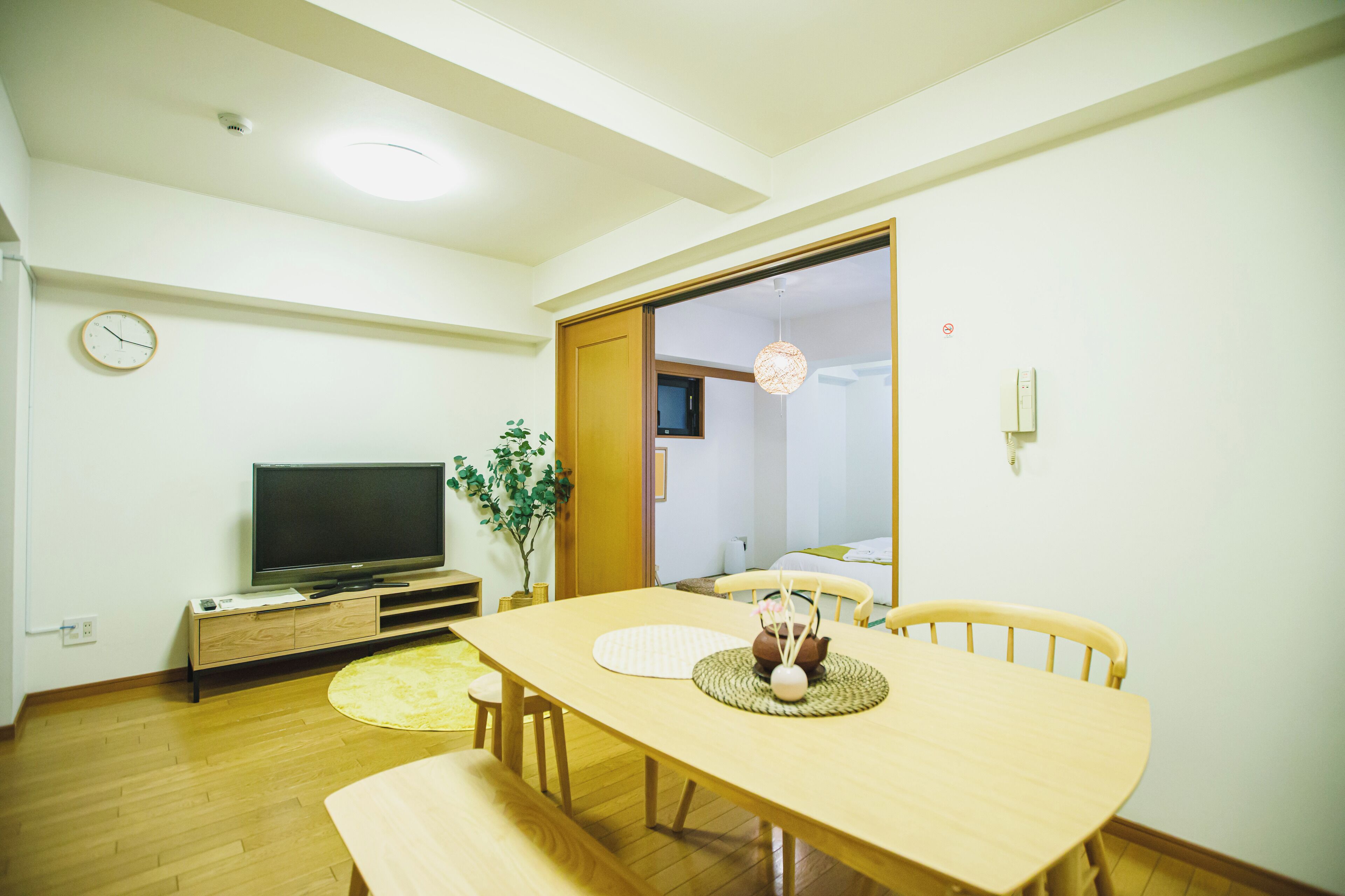 A dining area with a wooden table, chairs, and a television on a stand.