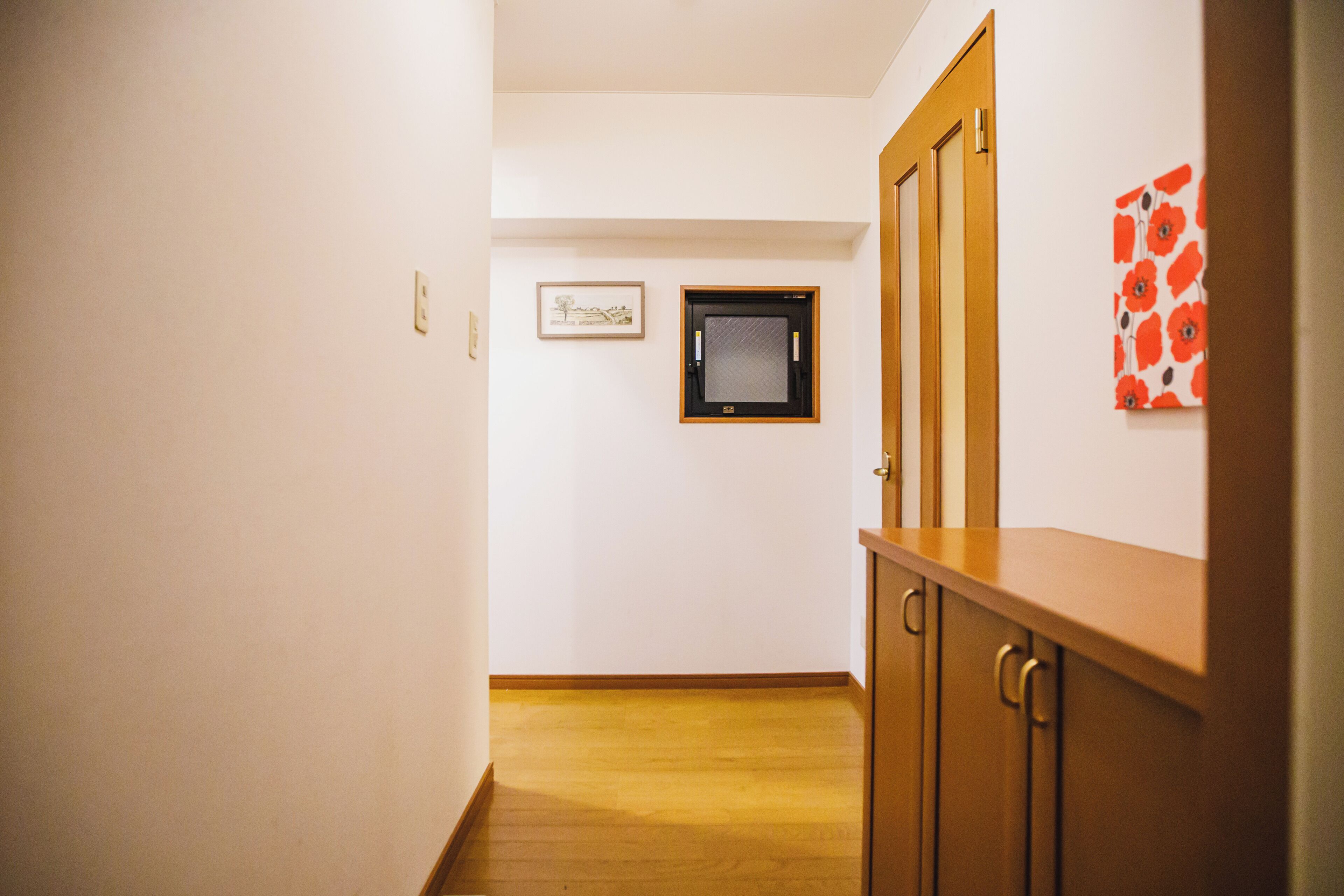A hallway with wooden flooring, a door, and a wall-mounted TV.