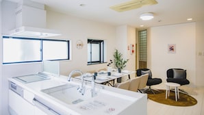 A modern kitchen with a large island, a dining area with a table and chairs, and a seating area with a sofa and a small side table. - R Residence Tanimachi (Osaka)