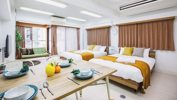 A hotel room with two beds, a dining table with plates and cutlery, and a sofa in the background. - R Residence Tanimachi (Osaka)