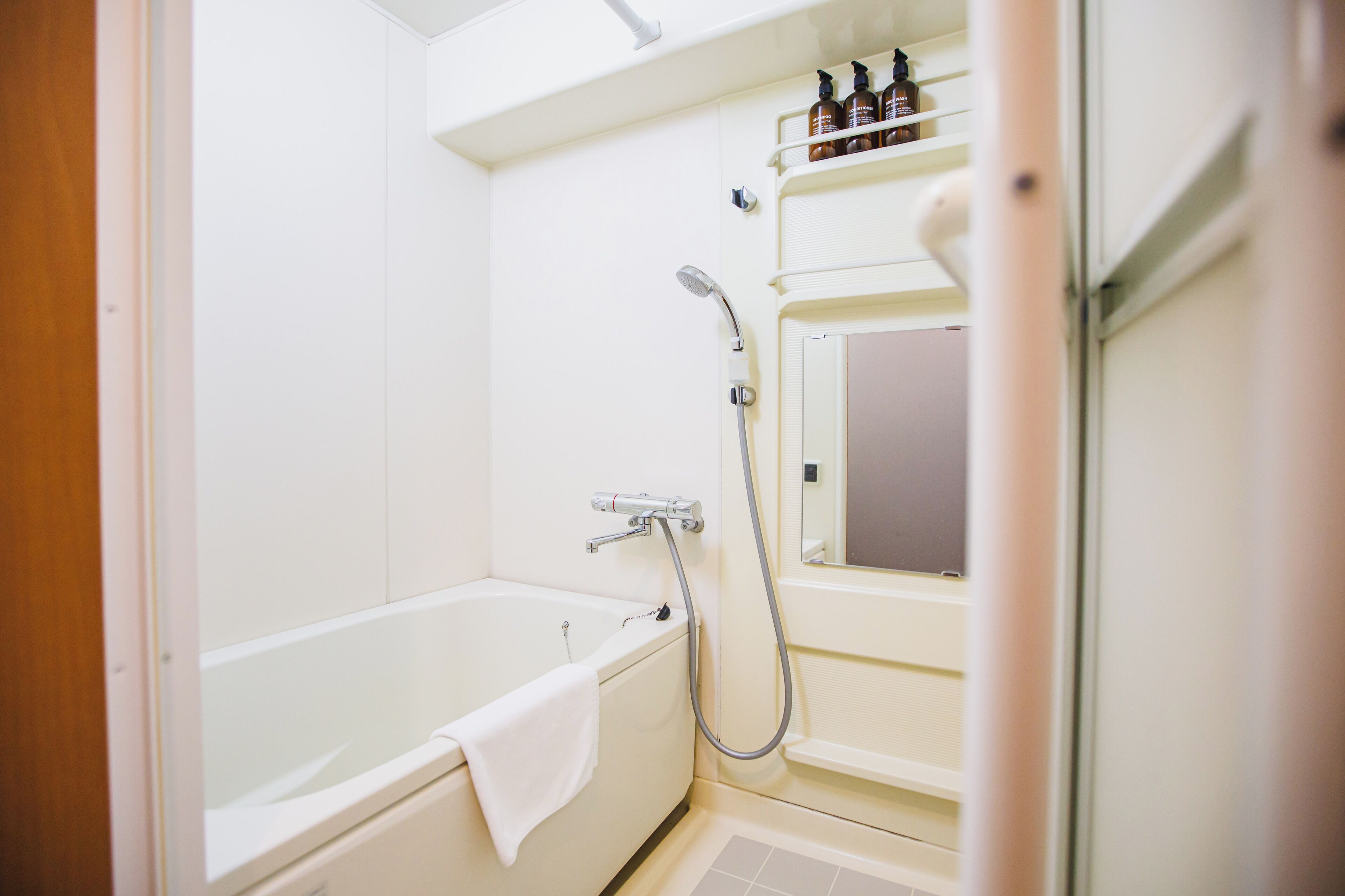 Un baño con bañera, ducha y un estante con artículos de aseo.