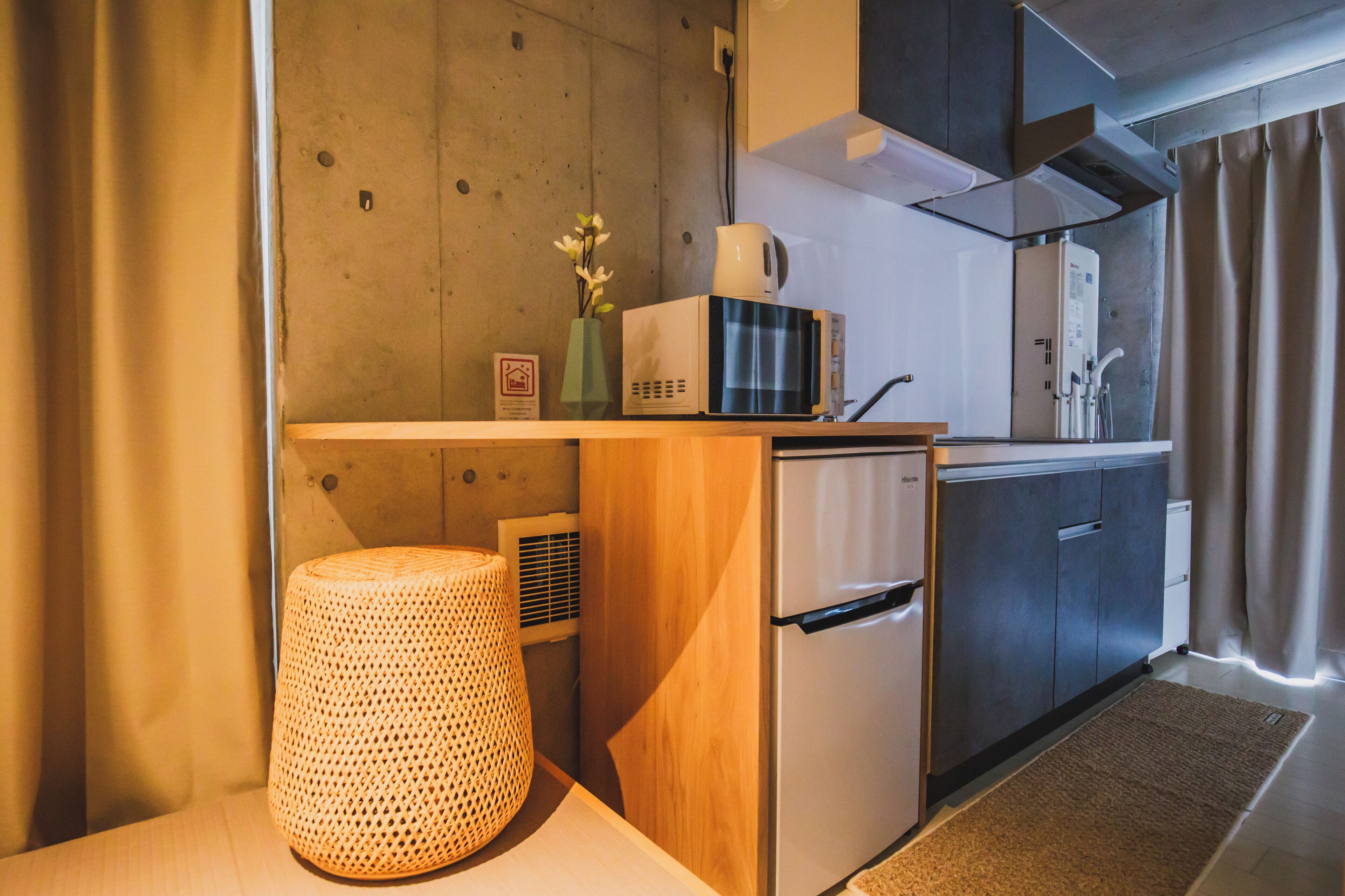 A compact kitchenette with a microwave, a small refrigerator, a sink, and a woven basket.
