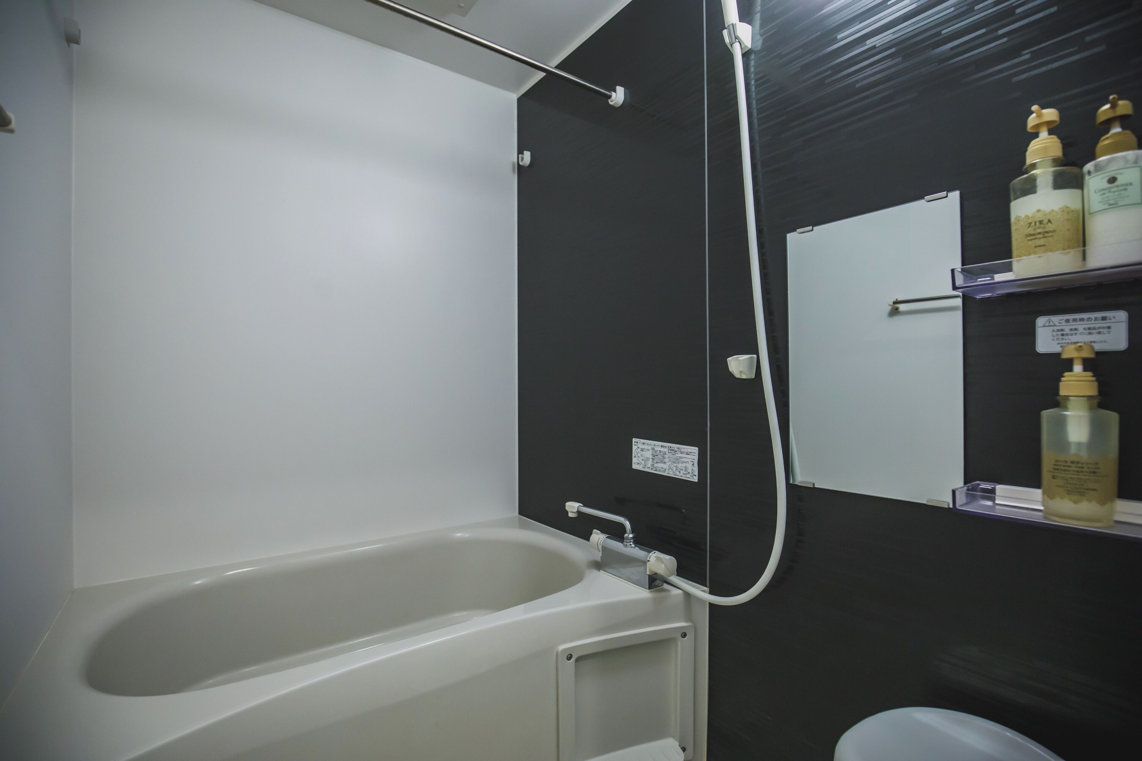 Un bagno con vasca, doccia e un ripiano con articoli da toilette.