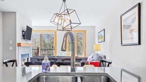 A modern kitchen with a stainless steel sink, a built-in oven, and a pendant light fixture.