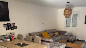 A modern living room with a wooden dining table, grey sofa, and a coffee table. - House 10 min from the sea With garden and swimming pool (Fréjus)