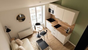 A compact kitchen with a dining area, a round mirror, and a view of the outside balcony. - Dify Lucky - 10 Min Centre de Lyon (Villeurbanne)