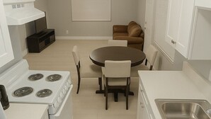 A modern kitchen with white cabinetry, a stove, a dining table with chairs, and a built-in sink. - Cozy 2BR 2BA on Fremont street 3 min walk from Fremont experience. (Las Vegas)