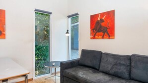 A modern living room with a grey sofa, a small round table, and a window with a view of greenery.