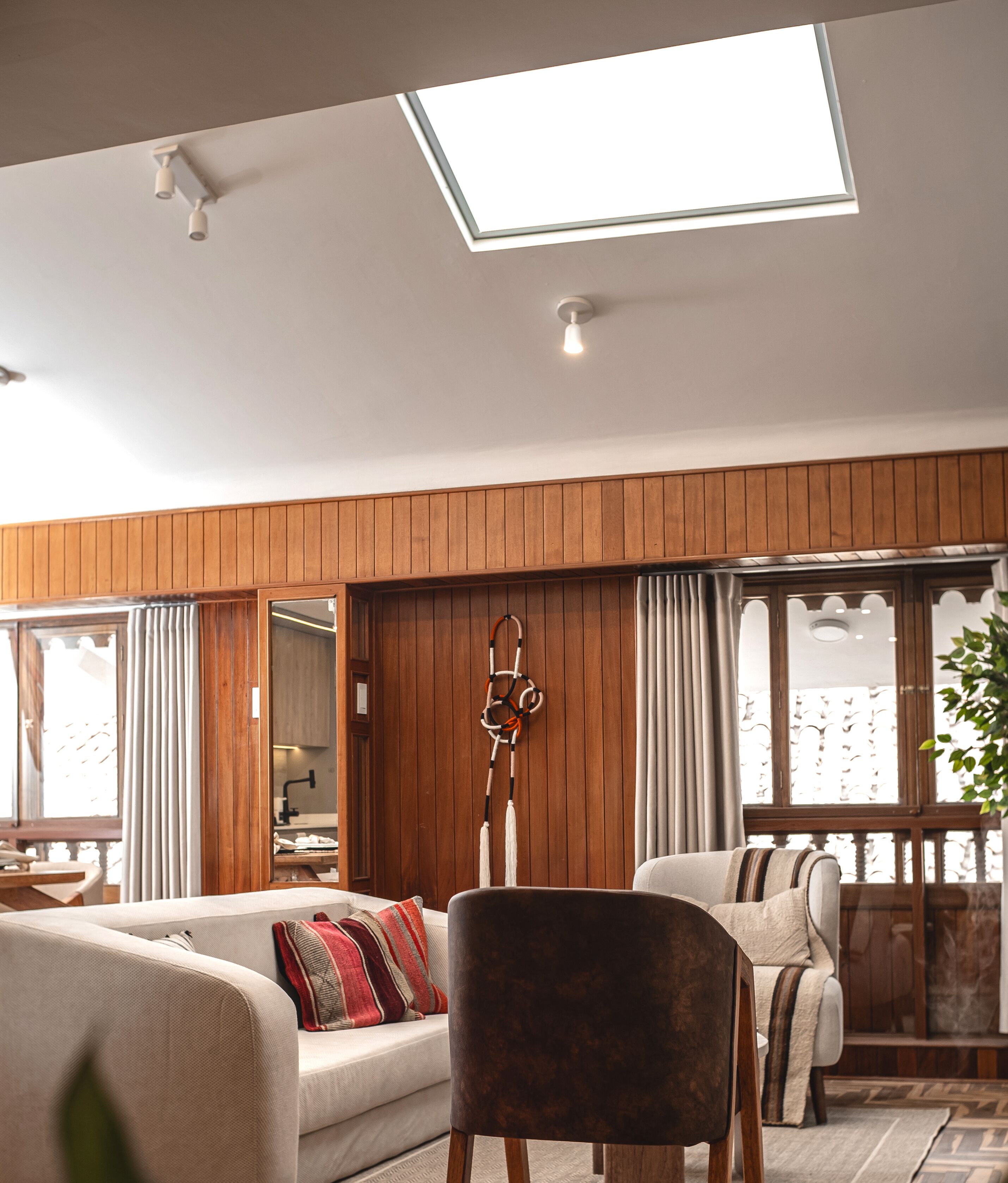 A modern living room with a sofa, armchair, and a hanging decorative item.