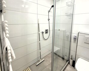 A modern bathroom with a glass shower enclosure, a white towel rack, and a toilet with a bidet attachment. - Winterberg Apartment With Free Garage (Winterberg)