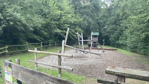 A playground with wooden structures and a wooden fence. - Spacious 80 m² vacation apartment with terrace for 4 people (Mörlenbach)