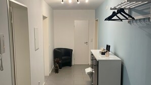 A hallway with a black chair, a white door, and a white cabinet with a towel and a small plant on top. - Spacious 80 m² vacation apartment with terrace for 4 people (Mörlenbach)