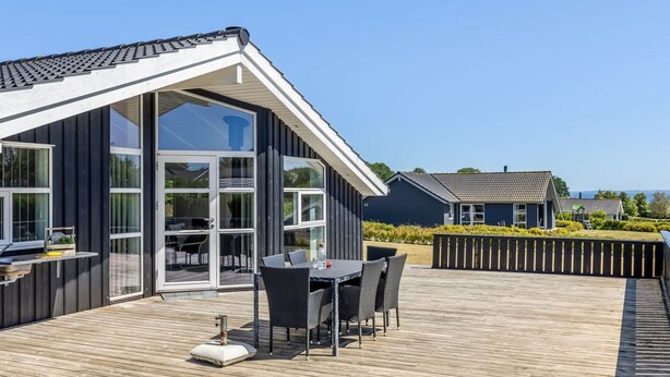 Ein modernes Gebäude mit einer großen Glasfassade und einer Terrasse mit Gartenmöbeln.