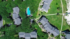 Vista aerea di un quartiere residenziale con case, una piscina e un prato curato.