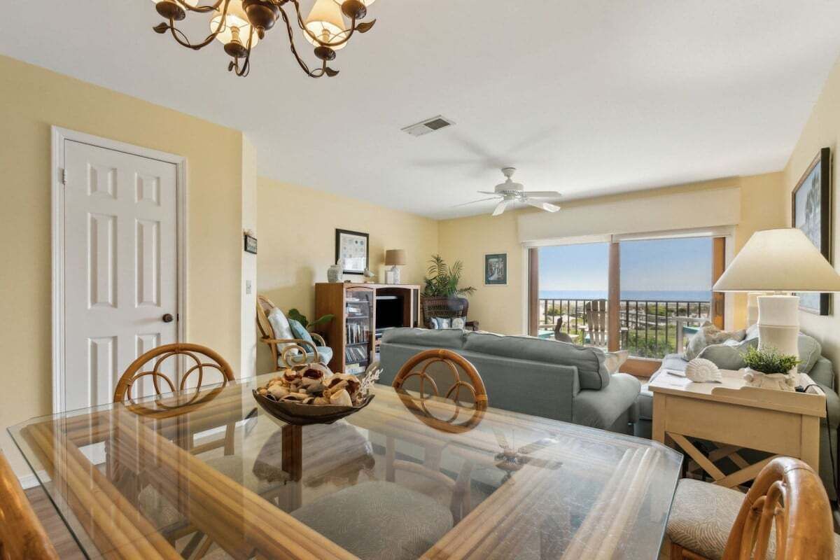 A dining area with a glass table, chairs, and a bowl of snacks.
