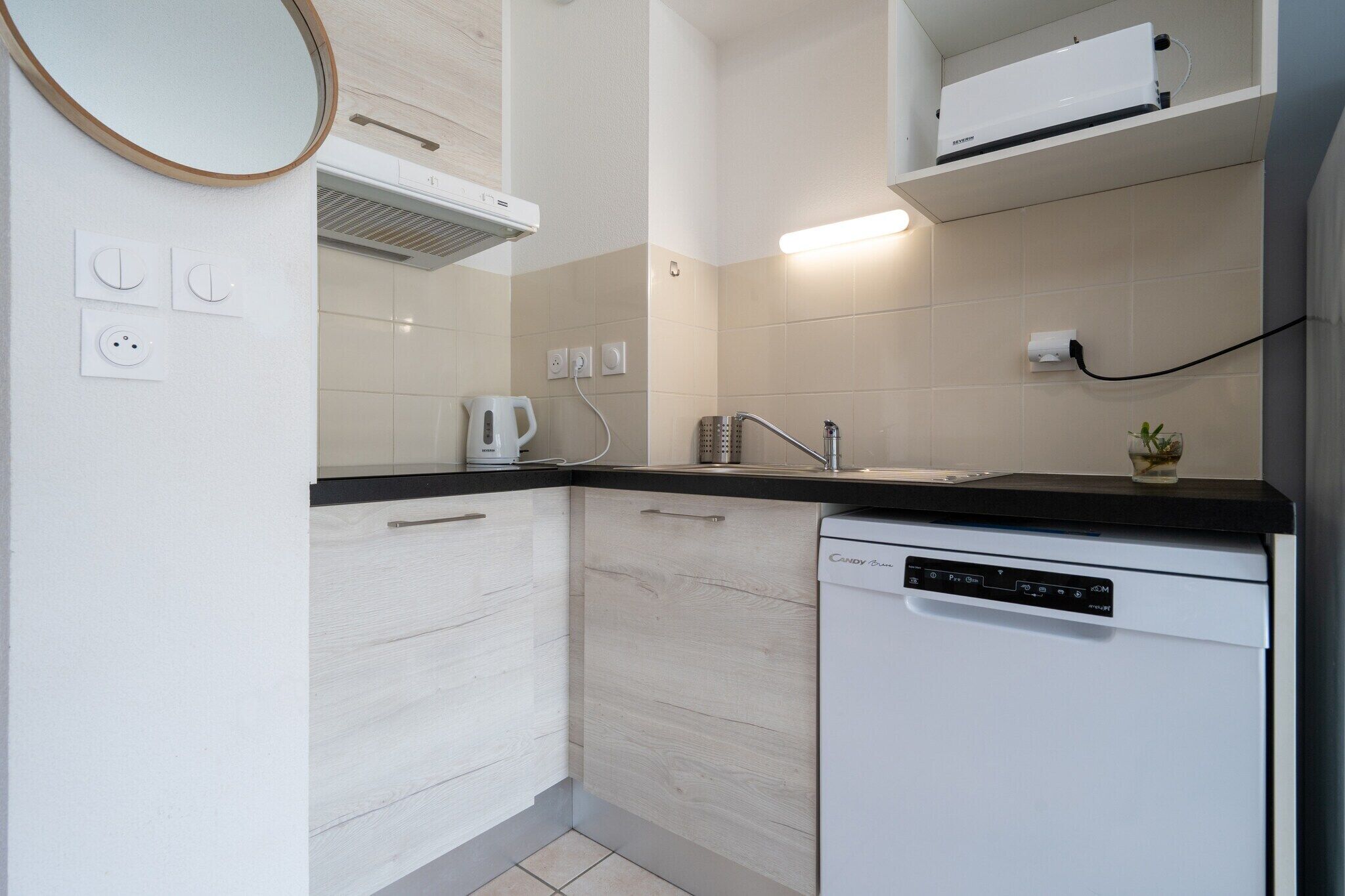 A modern kitchen with a dishwasher, a kettle, and a coffee maker.